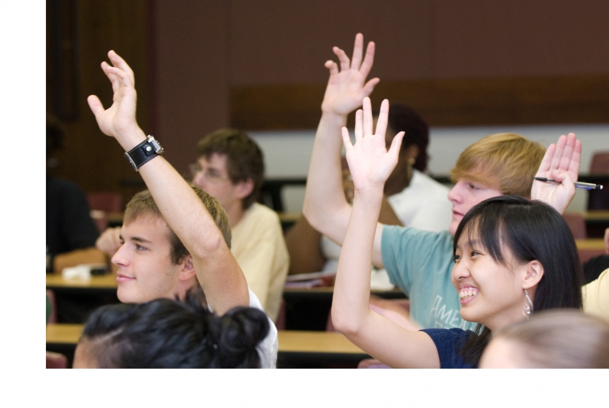 Multiple Students raising their hands in a classroom setting